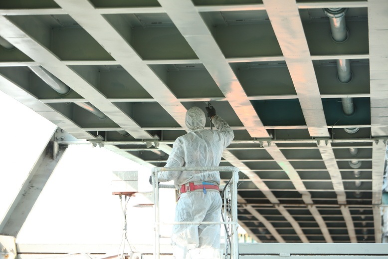 professional painter using air sprayer to paint industrial building